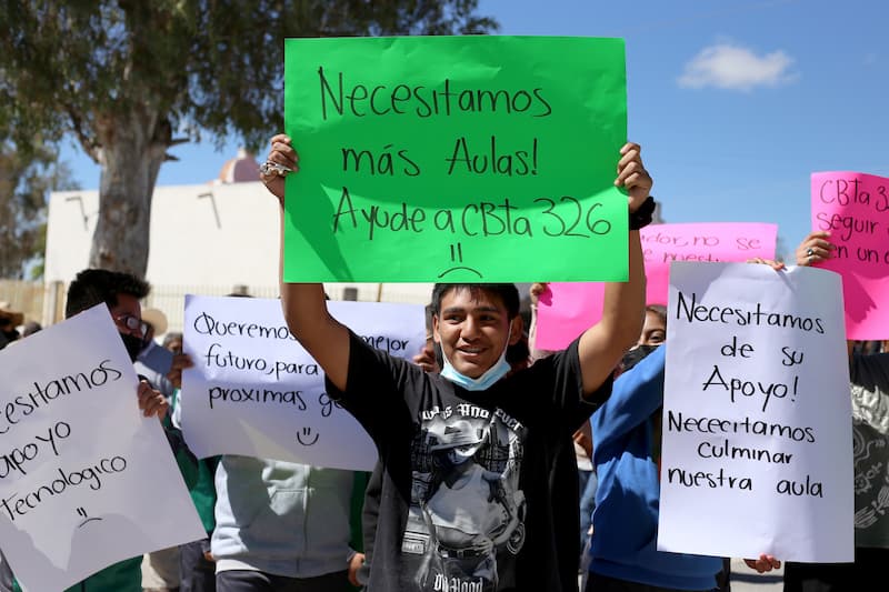Jóvenes de bachillerato muestran cartulinas con peticiones de aulas al gobernador Mauricio Kuri en Cazadero, San Juan del Río